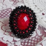 Bague Midnight in Paris brodée avec un cabochon ovale facettée de couleur Rouge à laquelle s'ajoute des rocailles Noires et Rouges, perles rondes facettées aplaties. Monté sur bague Laiton Argentée